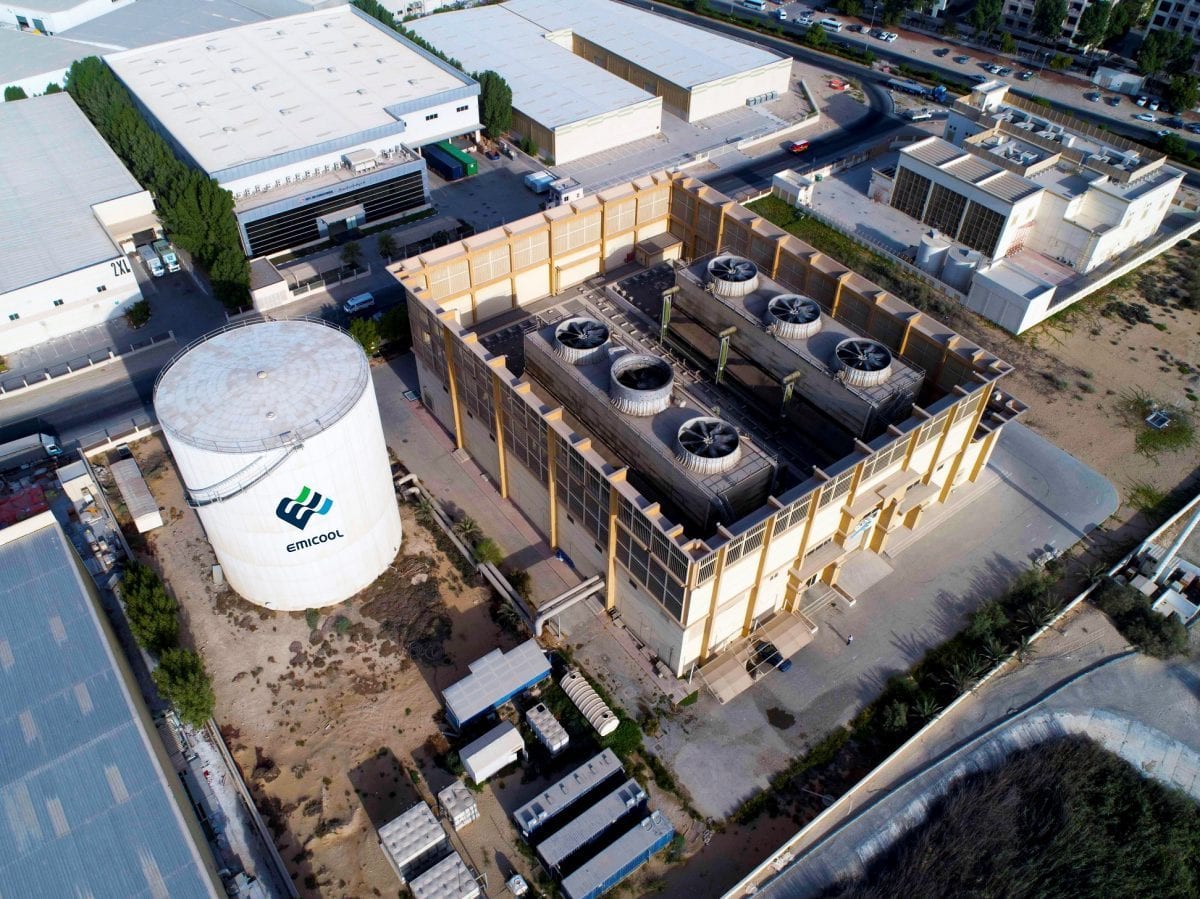 Aerial view of a UAE district cooling plant complex with TES tank and cooling-tower bank.